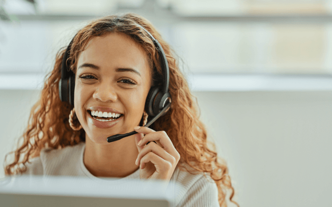 Valores Bancolombia contacto Foto de una mujer con cabello color cobrizo y con una diadema de call center, sonriendo mientras consulta en Valores Bancolombia su contacto para comunicarse de forma directa y clara con los asesores.